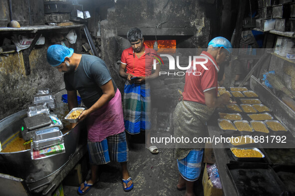 Workers make traditional fruit cake in a wood fire oven at a 100-year-old bakery ahead of Christmas celebrations in Kolkata, India, on Decem...