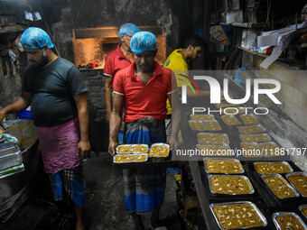 Workers make traditional fruit cake in a wood fire oven at a 100-year-old bakery ahead of Christmas celebrations in Kolkata, India, on Decem...