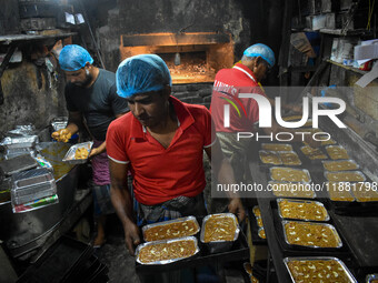 Workers make traditional fruit cake in a wood fire oven at a 100-year-old bakery ahead of Christmas celebrations in Kolkata, India, on Decem...