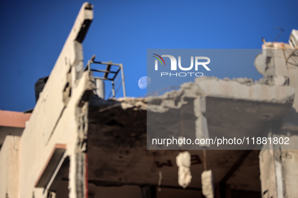 A general view shows the moon appearing behind a destroyed building in Deir al-Balah, on December 19, 2024, as the war between Israel and Ha...