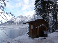 Waste bins under a wooden shelter in a snowy forest highlight local waste management efforts in a winter landscape in Grainau, Lake Eibsee,...