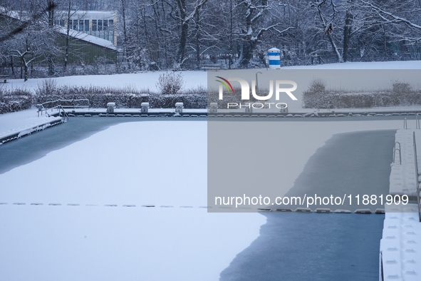 In Gauting, Bavaria, Germany, on January 6, 2021, the public swimming pool is blanketed in snow, with a red slide and surrounding trees crea...