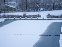 In Gauting, Bavaria, Germany, on January 6, 2021, the public swimming pool is blanketed in snow, with a red slide and surrounding trees crea...