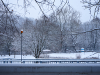 In Gauting, Bavaria, Germany, on January 6, 2021, the public swimming pool is blanketed in snow, with a red slide and surrounding trees crea...