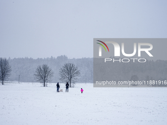 In Gauting, Bavaria, Germany, on January 6, 2021, a family spends a snowy day outdoors, with a child playing in a snow-covered field while t...