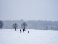 In Gauting, Bavaria, Germany, on January 6, 2021, a family spends a snowy day outdoors, with a child playing in a snow-covered field while t...