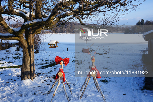 In Wessling, Bavaria, Germany, on January 9, 2021, decorative wooden reindeer adorned with red bows stand in a snow-covered park near the fr...