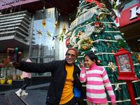 People take a selfie in front of an artificial Christmas tree set at the entrance of a mall in Kathmandu, Nepal, on December 19, 2024, ahead...