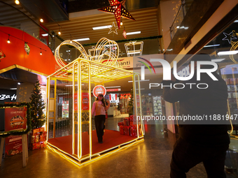 A Nepali couple poses and takes photos in front of an artificial Christmas tree set at the entrance of a mall in Kathmandu, Nepal, on Decemb...