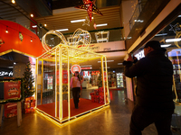 A Nepali couple poses and takes photos in front of an artificial Christmas tree set at the entrance of a mall in Kathmandu, Nepal, on Decemb...