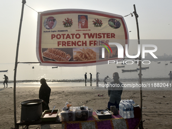 A potato twister French fry seller waits for his customer during the Mahim festival on a beach in Mumbai, India, on December 19, 2024. (