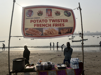 A potato twister French fry seller waits for his customer during the Mahim festival on a beach in Mumbai, India, on December 19, 2024. (