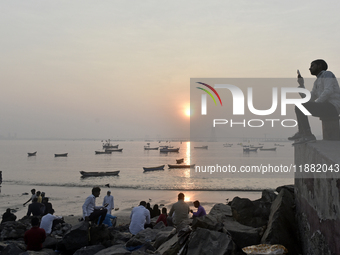 People enjoy the sunset on a beach in Mumbai, India, on December 19, 2024. (