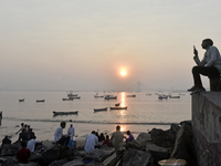 People enjoy the sunset on a beach in Mumbai, India, on December 19, 2024. (