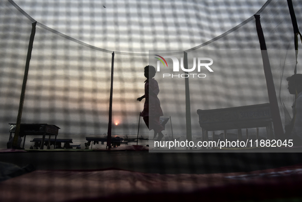 A child jumps on a round trampoline with an enclosure net near a sea beach in Mumbai, India, on December 19, 2024. 