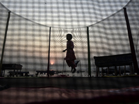 A child jumps on a round trampoline with an enclosure net near a sea beach in Mumbai, India, on December 19, 2024. (