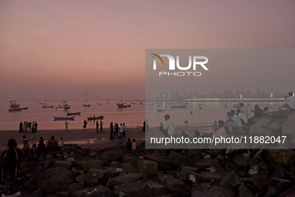 People enjoy the sunset near a sea beach in Mumbai, India, on December 19, 2024. 