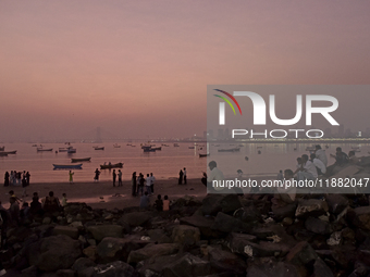 People enjoy the sunset near a sea beach in Mumbai, India, on December 19, 2024. (