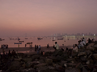 People enjoy the sunset near a sea beach in Mumbai, India, on December 19, 2024. (