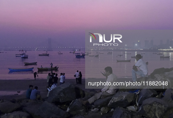 People enjoy the sunset near a sea beach in Mumbai, India, on December 19, 2024. 