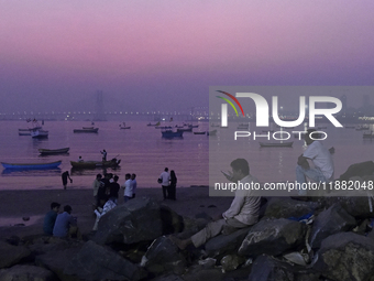 People enjoy the sunset near a sea beach in Mumbai, India, on December 19, 2024. (