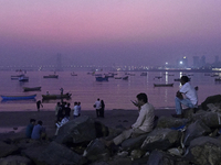 People enjoy the sunset near a sea beach in Mumbai, India, on December 19, 2024. (