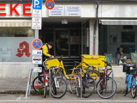 In Munich, Bavaria, Germany, on December 19, 2024, a Deutsche Post postman delivers letters to a residential building, with his yellow deliv...