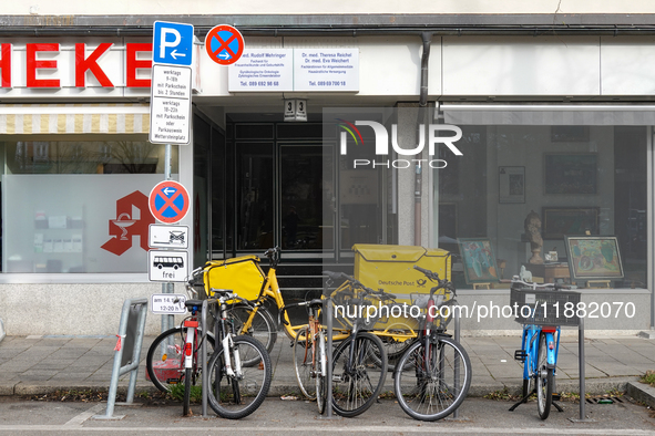 In Munich, Bavaria, Germany, on December 19, 2024, a Deutsche Post delivery bicycle is parked outside a residential building as postal worke...