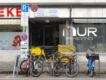 In Munich, Bavaria, Germany, on December 19, 2024, a Deutsche Post delivery bicycle is parked outside a residential building as postal worke...