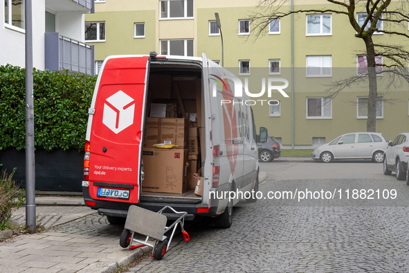 A DPD delivery van parks in front of a residential building while parcels are unloaded for delivery in Munich, Bavaria, Germany, on December...