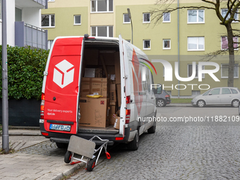 A DPD delivery van parks in front of a residential building while parcels are unloaded for delivery in Munich, Bavaria, Germany, on December...