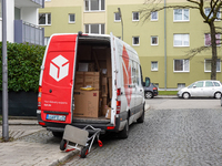 A DPD delivery van parks in front of a residential building while parcels are unloaded for delivery in Munich, Bavaria, Germany, on December...