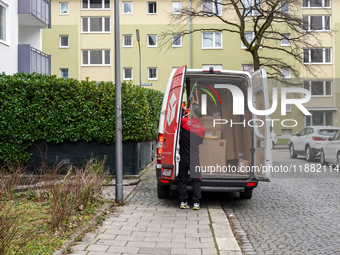 A DPD delivery van parks in front of a residential building while parcels are unloaded for delivery in Munich, Bavaria, Germany, on December...