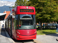 In Innsbruck, Austria, on September 22, 2024, a red tram bound for Claudiaplatz is at the Stift Wilten tram stop, against a backdrop of gree...