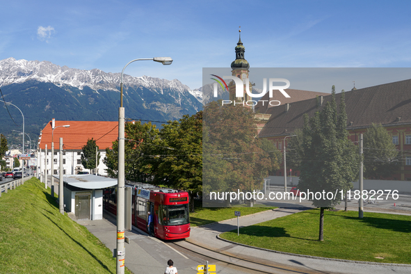 In Innsbruck, Austria, on September 22, 2024, a tram stops at Stift Wilten tram station, with the Wilten Basilica and the Tyrolean Alps in t...