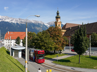 In Innsbruck, Austria, on September 22, 2024, a tram stops at Stift Wilten tram station, with the Wilten Basilica and the Tyrolean Alps in t...