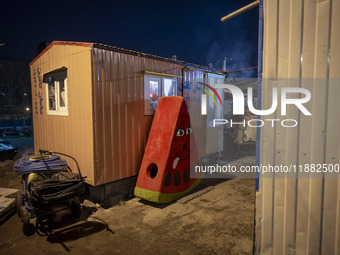 A watermelon-shaped doll is placed next to a container at a construction site during the pomegranate festival on Yalda Night Eve in the Abas...