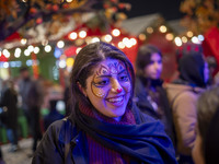 A young Iranian woman with a painting on her face smiles while participating in a pomegranate festival on Yalda Night Eve in the Abasabad to...