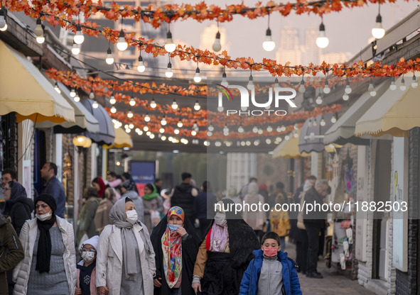 Iranian people walk under Yalda decorations during a pomegranate festival on Yalda Night Eve in the Abasabad tourism zone in central Tehran,...