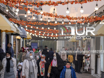 Iranian people walk under Yalda decorations during a pomegranate festival on Yalda Night Eve in the Abasabad tourism zone in central Tehran,...