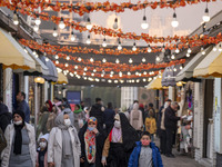 Iranian people walk under Yalda decorations during a pomegranate festival on Yalda Night Eve in the Abasabad tourism zone in central Tehran,...