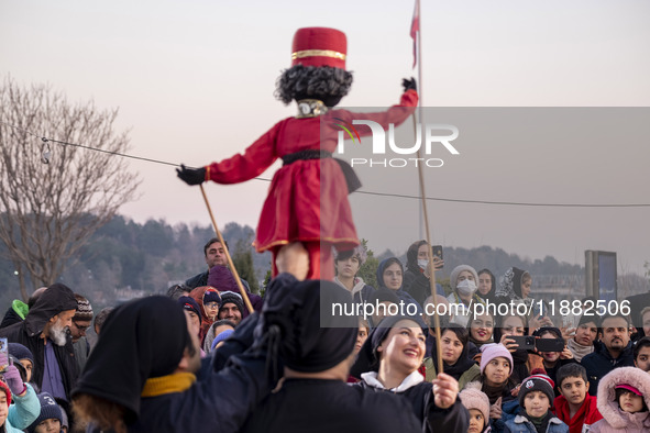 Young puppeteers perform with an Iranian traditional puppet during a pomegranate festival on Yalda Night Eve in the Abasabad tourism zone in...