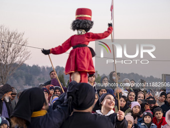 Young puppeteers perform with an Iranian traditional puppet during a pomegranate festival on Yalda Night Eve in the Abasabad tourism zone in...