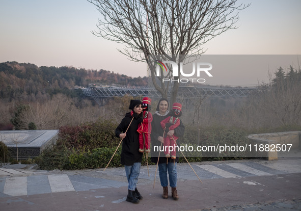 Two young female puppeteers pose for a photograph with two Iranian traditional puppets during a pomegranate festival on Yalda Night Eve in t...