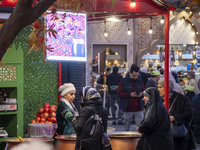 Iranian women shop for pomegranate molasses from a saleswoman while visiting a pomegranate festival on Yalda Night Eve in the Abasabad touri...