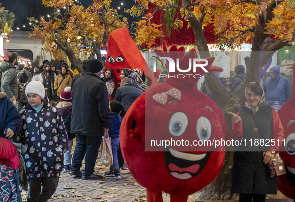 Iranian families pose for photographs with pomegranate and watermelon-shaped dolls during a pomegranate festival on Yalda Night Eve in the A...