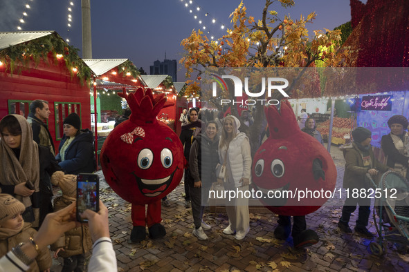 Iranian women pose for photographs with two pomegranate-shaped dolls during a pomegranate festival on Yalda Night Eve in the Abasabad touris...