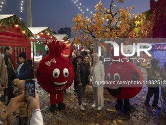 Iranian women pose for photographs with two pomegranate-shaped dolls during a pomegranate festival on Yalda Night Eve in the Abasabad touris...