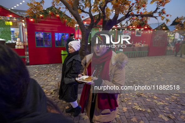 A young Iranian woman carries sweets as she walks past a Yalda decoration during a pomegranate festival on Yalda Night Eve in the Abasabad t...