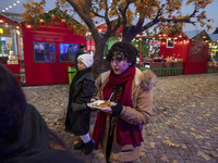 A young Iranian woman carries sweets as she walks past a Yalda decoration during a pomegranate festival on Yalda Night Eve in the Abasabad t...